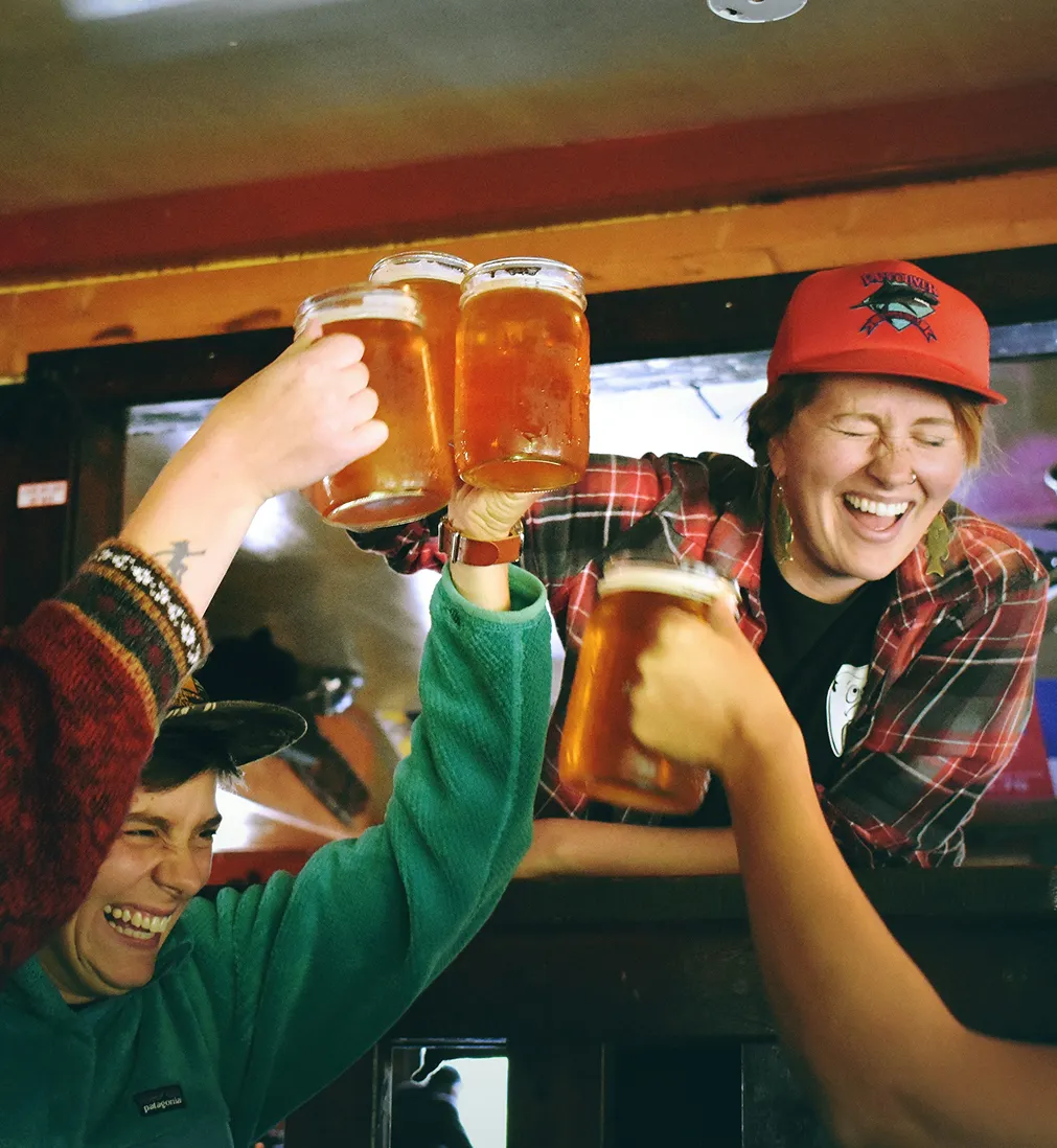 Drie makers proosten lachend met grote glazen bier