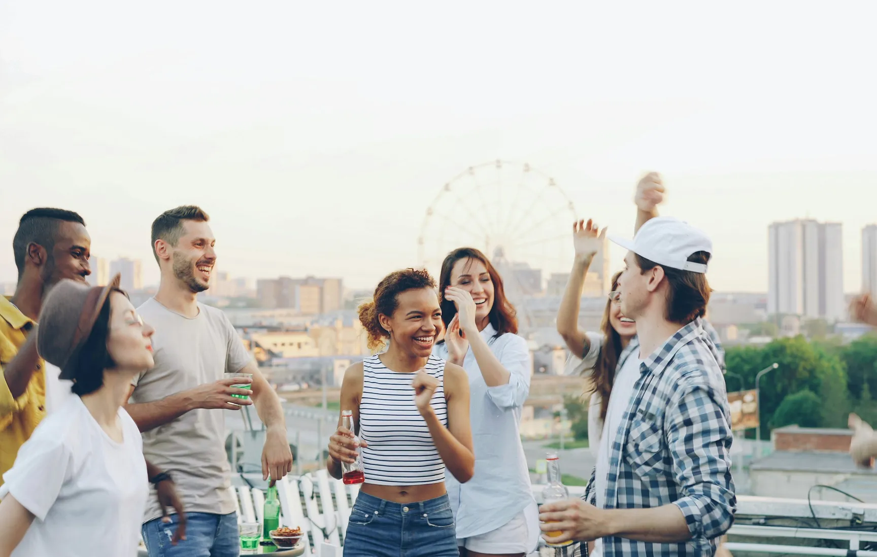 Een groep vrienden danst en lacht samen op een dakterras